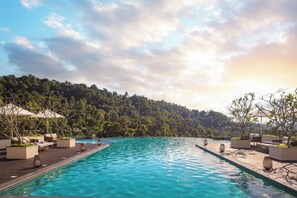 A swimming pool with lounge chairs and planters, surrounded by a forested hillside. - The Golden Crown Hotel (Kandy)