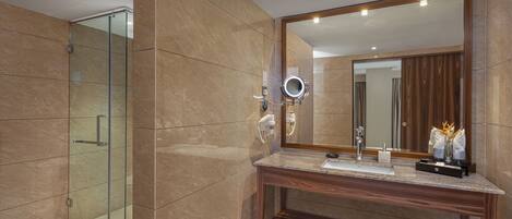 A modern bathroom with a glass shower enclosure, a wooden vanity, and a large mirror with a round light.