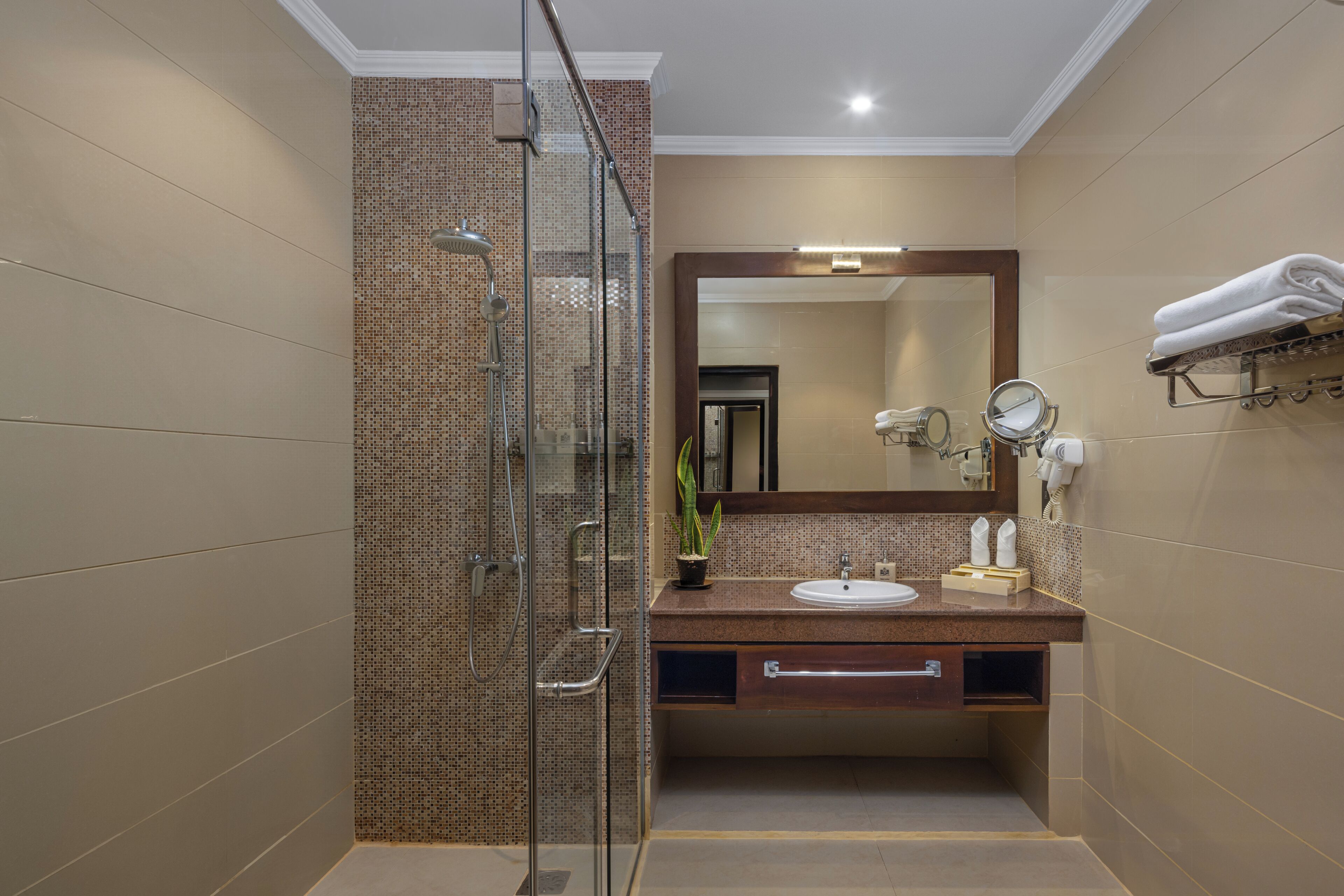 A modern bathroom with a glass shower enclosure, a sink with a mirror, and a towel rack.