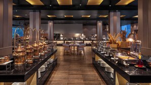 Un buffet composé de plusieurs tables de service, d’une table centrale où les convives peuvent s’asseoir et d’une variété de récipients et d’ustensiles pour servir les aliments.