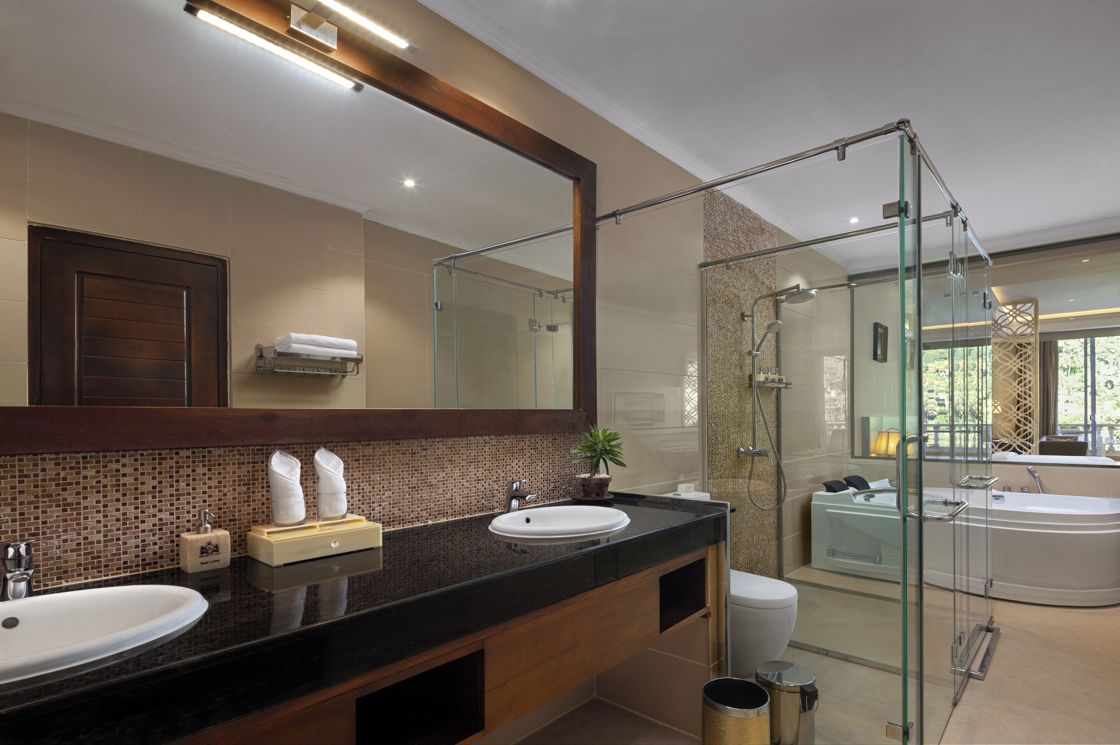 A modern bathroom with a large mirror, two sinks, a glass shower enclosure, and a bathtub.