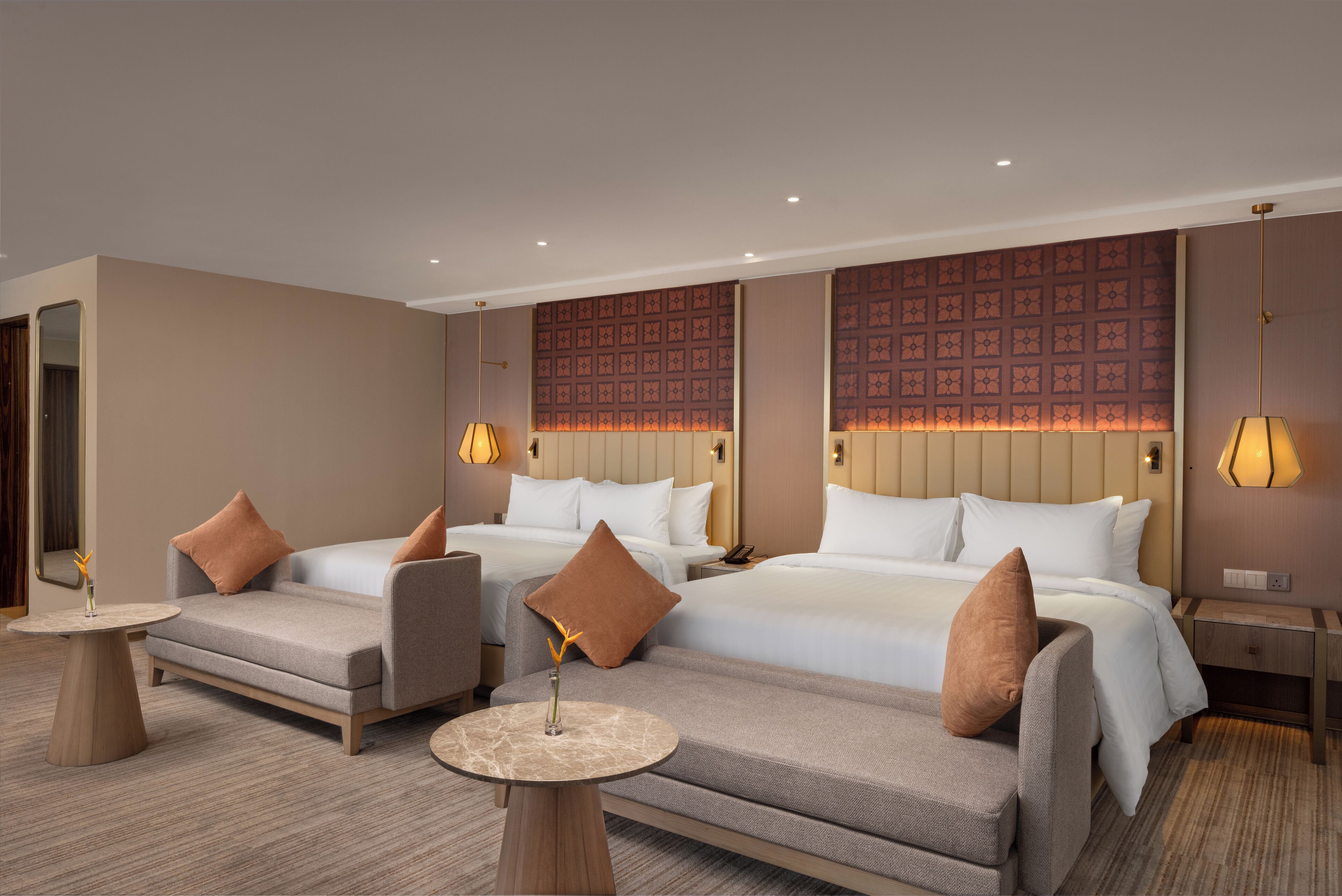 Quarto de hotel com duas camas, um sofá, uma mesinha e um abajur.