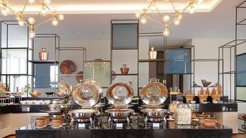 A buffet setup with multiple serving stations, overhead lighting, and decorative elements.