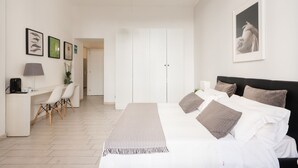 Quarto com cama, mesa de cabeceira, abajur e quadro emoldurado.