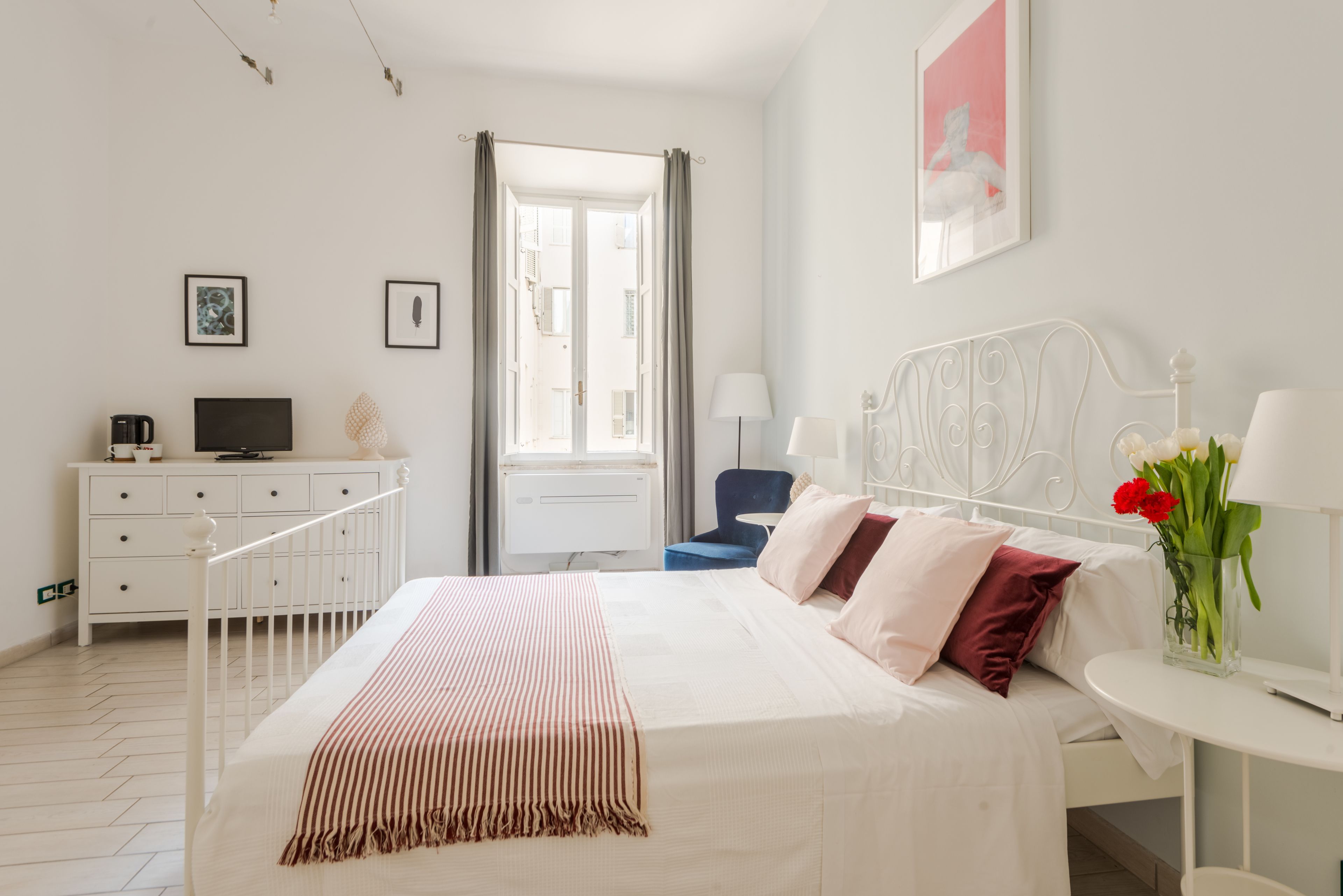 Habitación de hotel con cama, escritorio, silla, televisor y ventana con cortinas.
