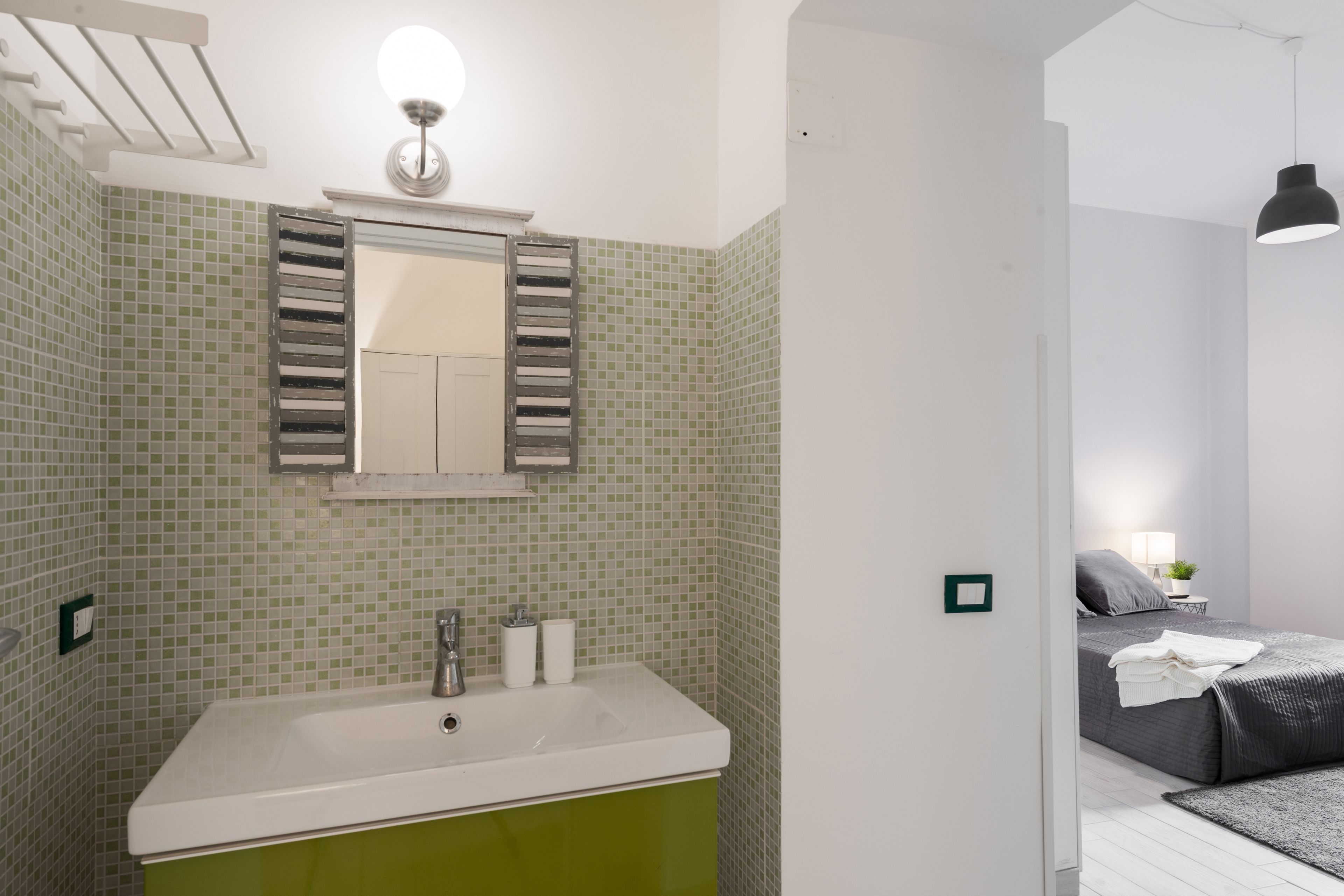 Une salle de bain avec un lavabo vert, un miroir et un espace douche.