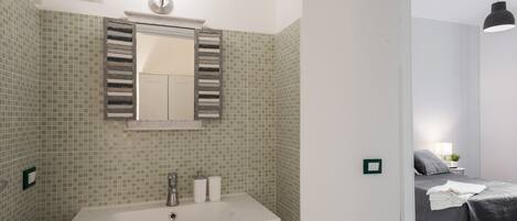 Une salle de bain avec un lavabo vert, un miroir et un espace douche.