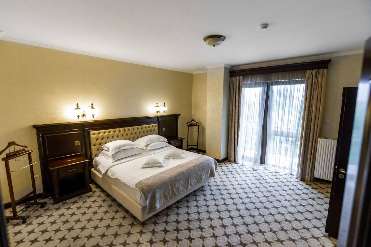 Habitación de hotel con una cama grande, una mesita de noche, un aparador y un armario.