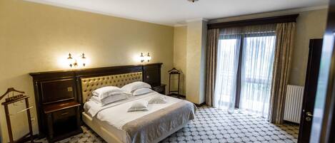 A hotel room with a large bed, a nightstand, a dresser, and a wardrobe.