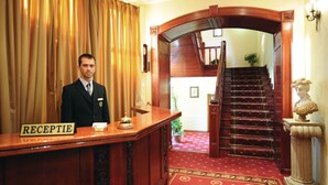 A reception area with a wooden desk labeled "RECEPTION," a staircase, and a bust statue. - Hotel Golden House (Craiova)