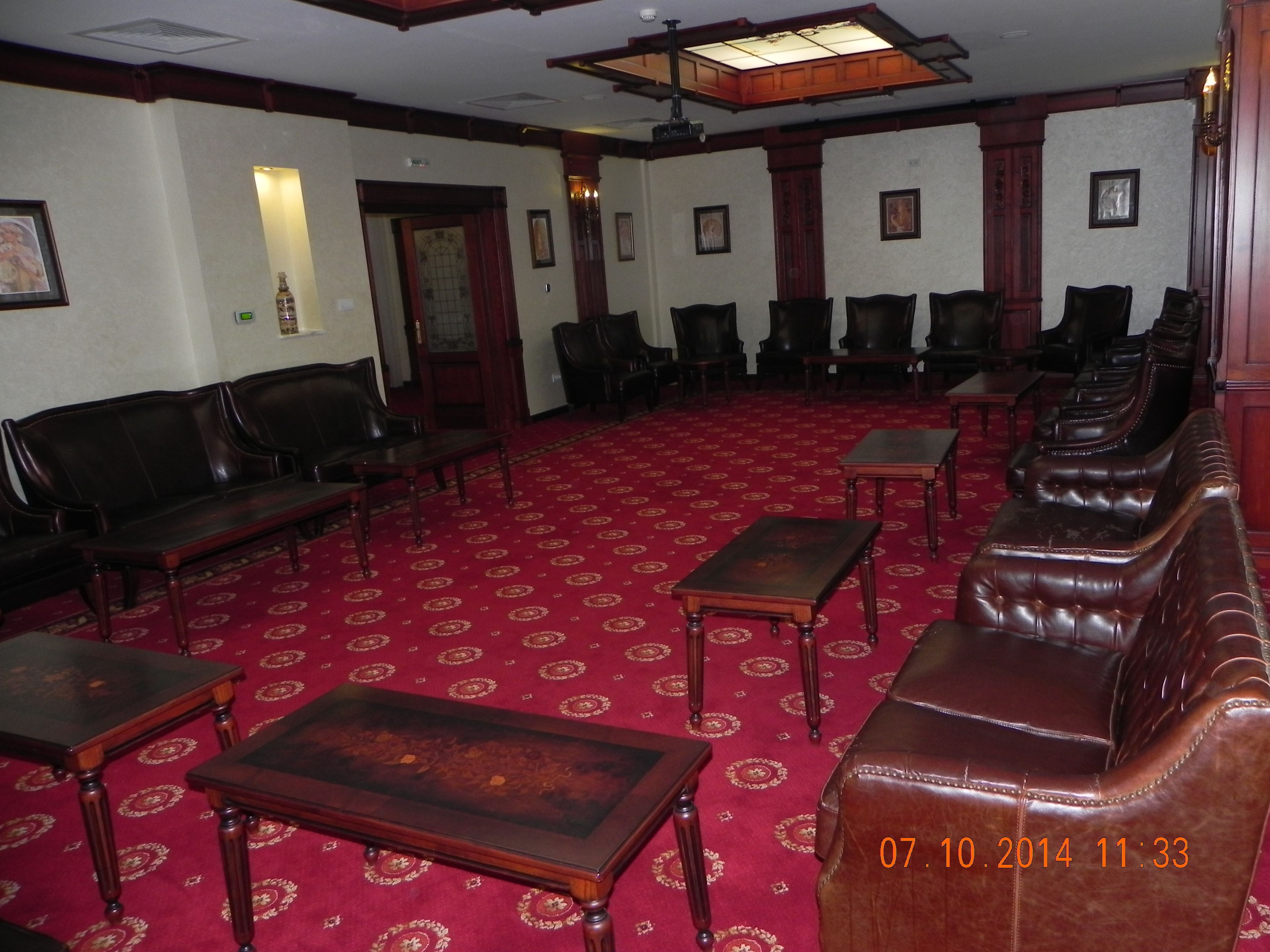 A room with a red carpet, wooden furniture, and framed pictures on the walls.