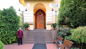 A hotel entrance with a wooden door, steps, and a bench. - Hotel Golden House (Craiova)