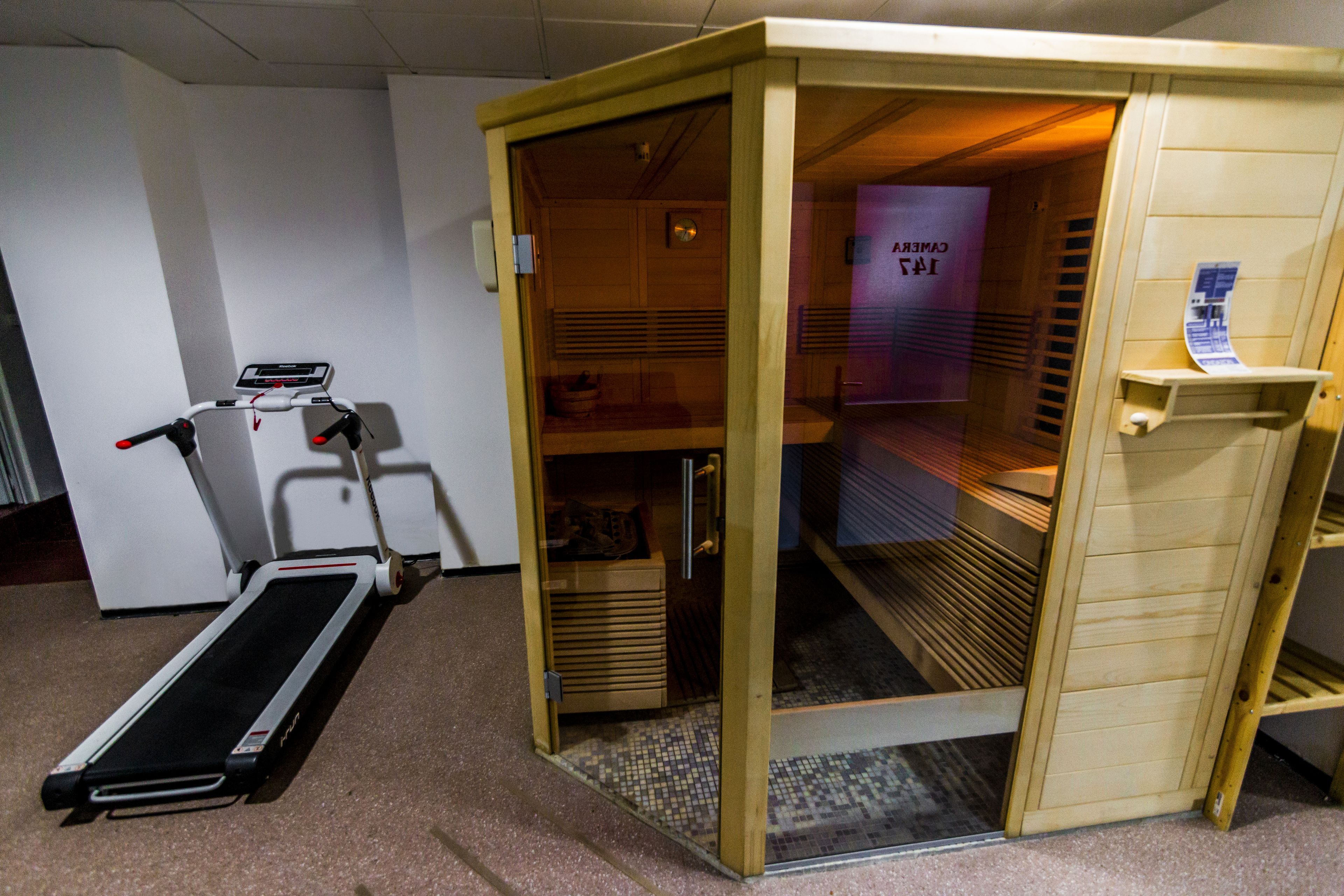 A sauna room with a wooden door, a bench, and a towel rack.