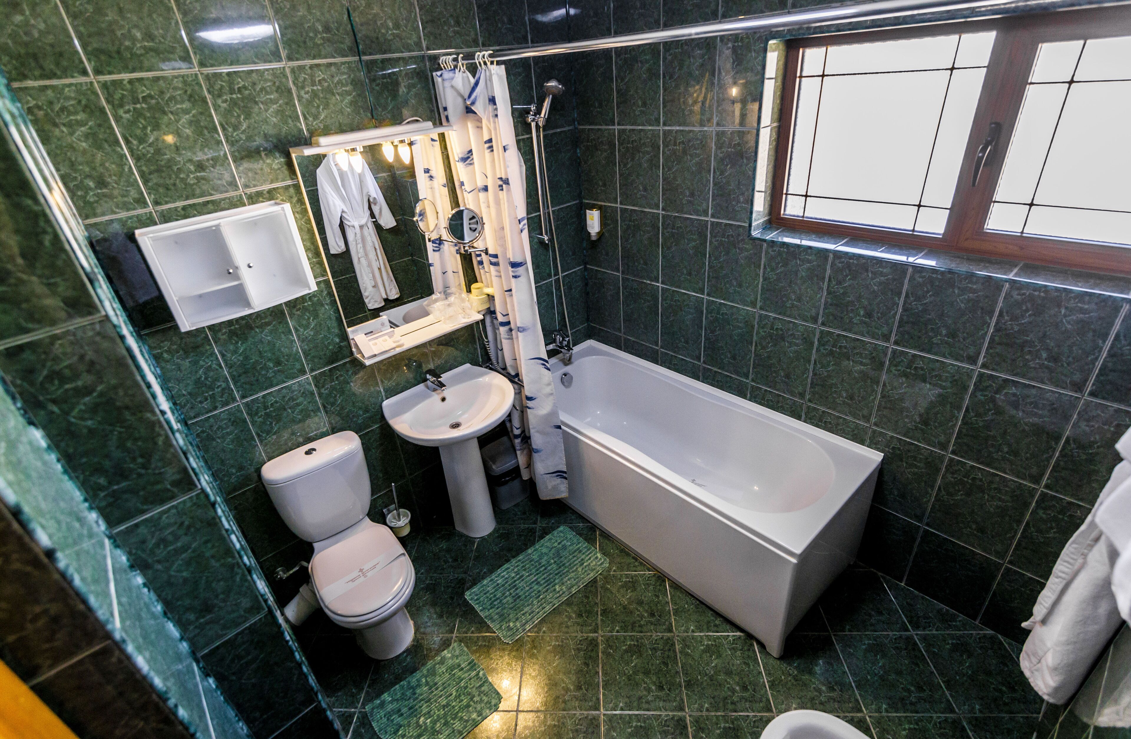 A bathroom with a bathtub, toilet, sink, and a window.