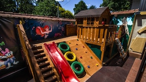 A children's play area with a slide, climbing wall, and a mural on the wall. - Hotel Golden House (Craiova)