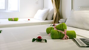Una cama bien hecha con toallas verdes, una rosa, una almohada blanca y un libro sobre la cama.