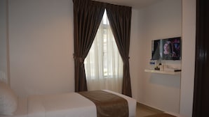 Quarto de hotel com duas camas, televisão na parede e janela com cortinas.