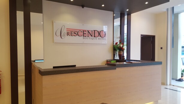 Um balcão de recepção com uma placa indicando "CRESCENDO BOUTIQUE HOTEL".