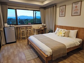 Camera d'albergo con un letto, una scrivania, due sedie, un piccolo frigorifero e vista sull'esterno.