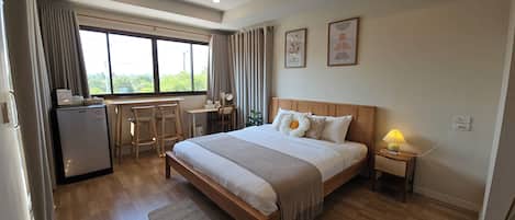 Un dormitorio con cama, mesita de noche, lámpara y un escritorio con sillas.