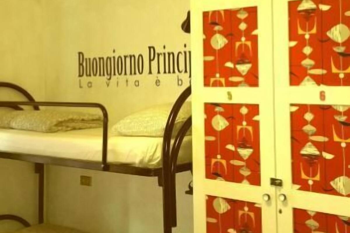 A bunk bed room with a wall sign reading "Buongiorno Principe" and a wardrobe with a red and white pattern.