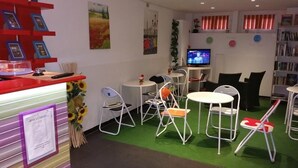 A room with multiple seating areas, a television, and a bookshelf. - Hostel Lumiere (Milan)