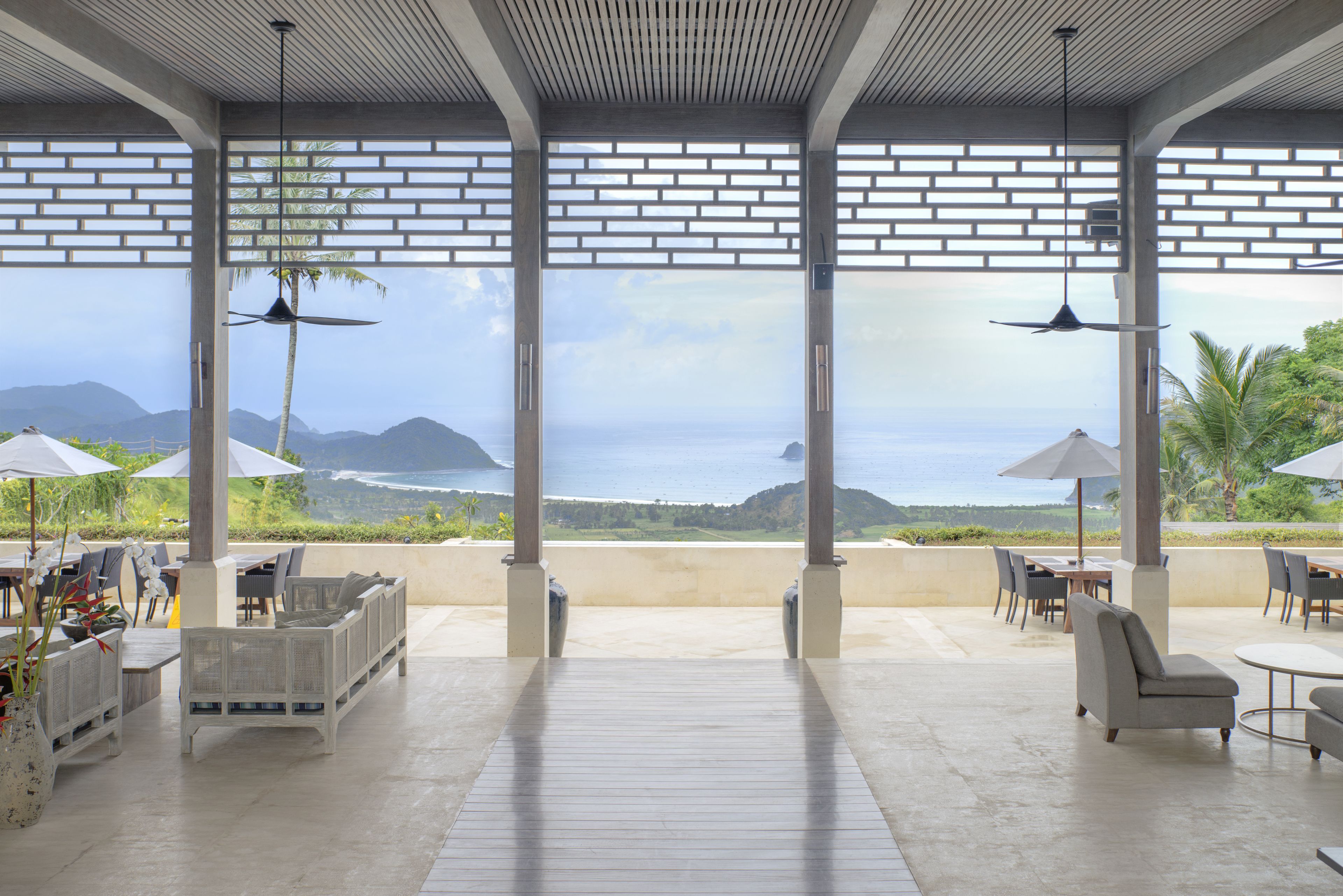 Un patio al aire libre con mobiliario, sombrillas y vistas al océano.
