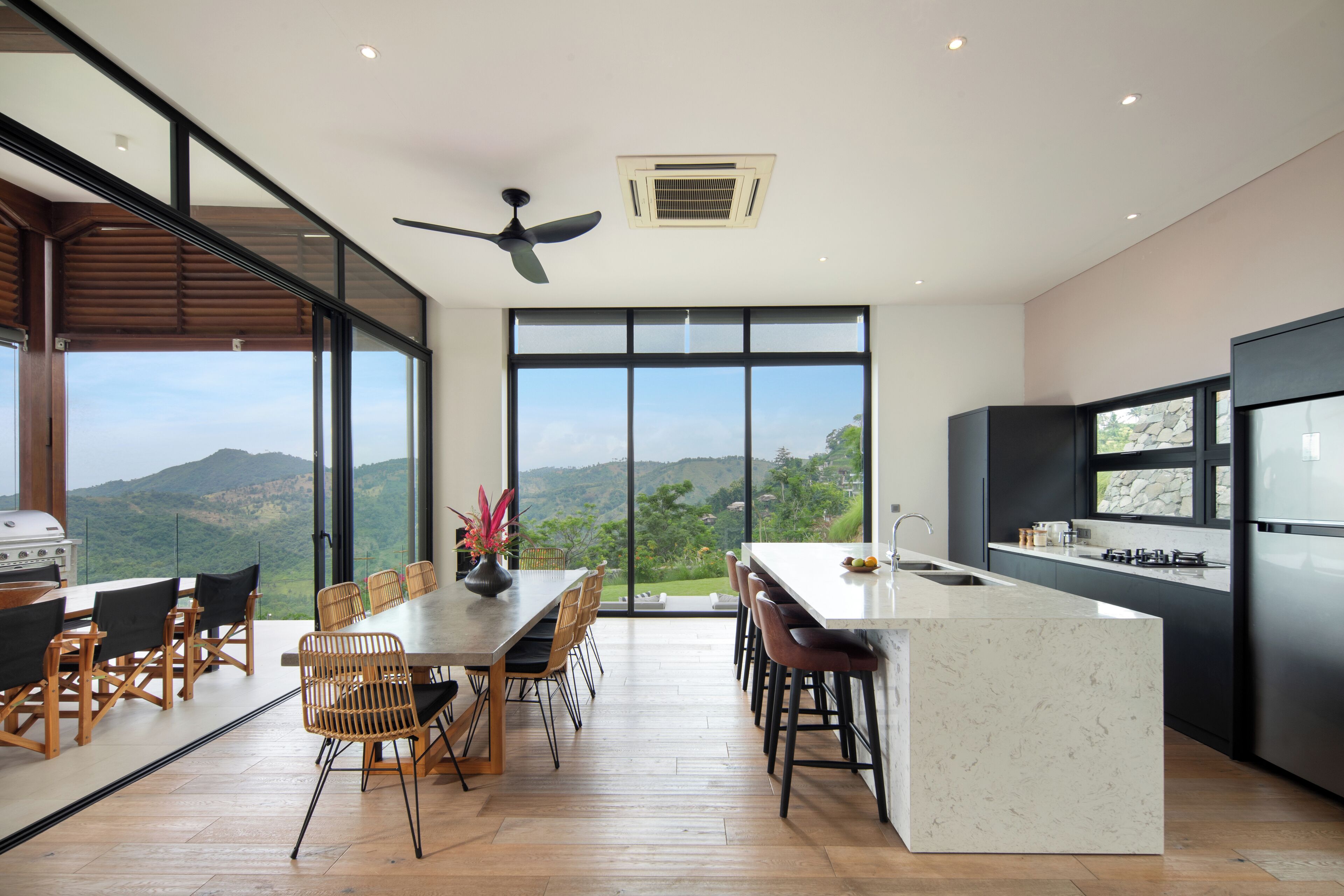 Une cuisine moderne dotée d’un grand îlot central, d’un coin repas avec vue et d’un ventilateur de plafond.