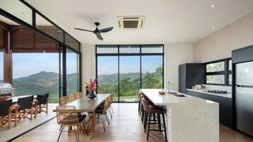 Une cuisine moderne dotée d’un grand îlot central, d’un coin repas avec vue et d’un ventilateur de plafond.