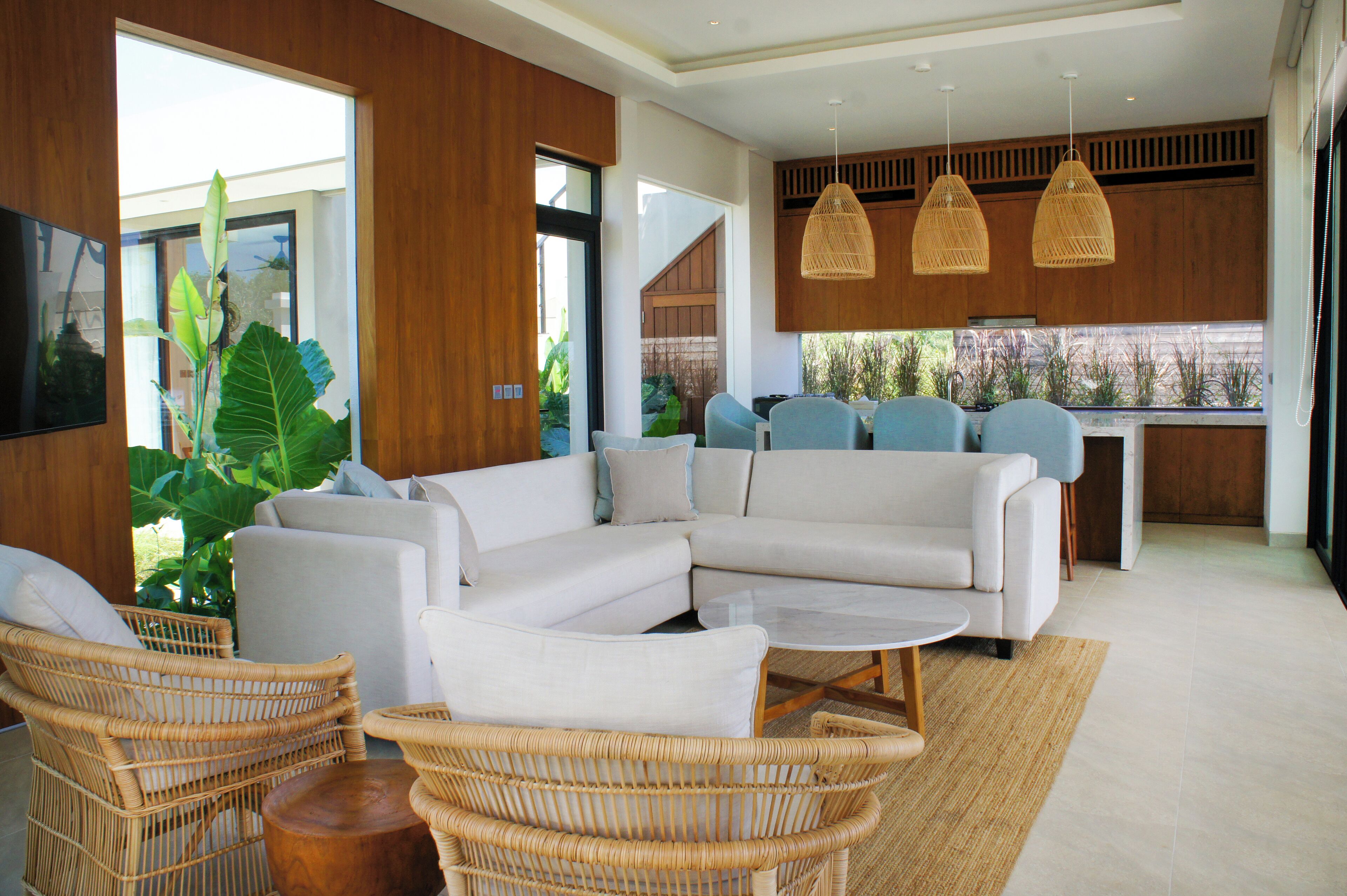 Un salon moderne avec un canapé d’angle, des fauteuils en osier et une table basse.