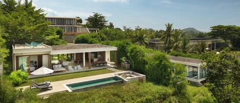 A modern house with a pool, outdoor seating, and lush greenery.