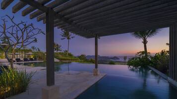 Una piscina al aire libre, sombrillas, sillones reclinables de piscina