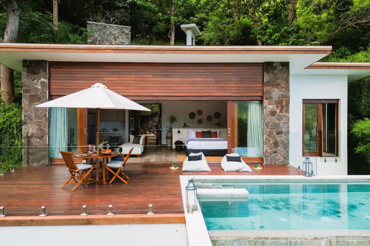 Una casa moderna con piscina, terraza de madera y zona de comedor.