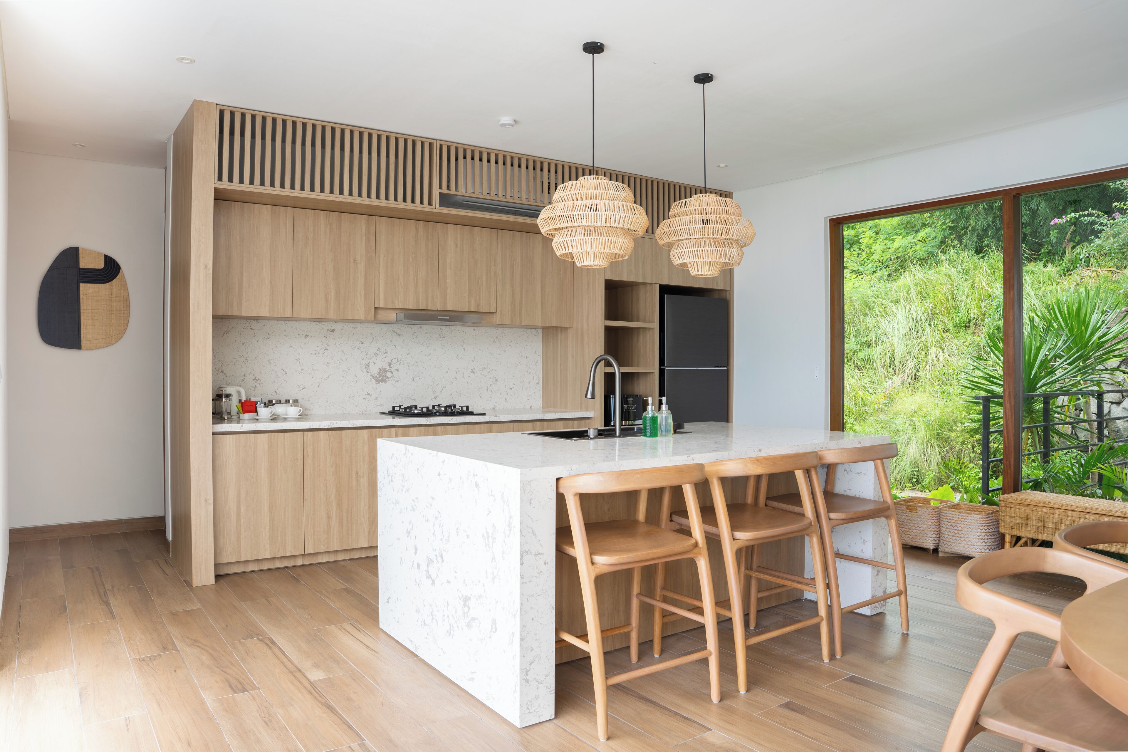 Une cuisine moderne dotée d’un grand îlot central, de meubles en bois et de luminaires suspendus.