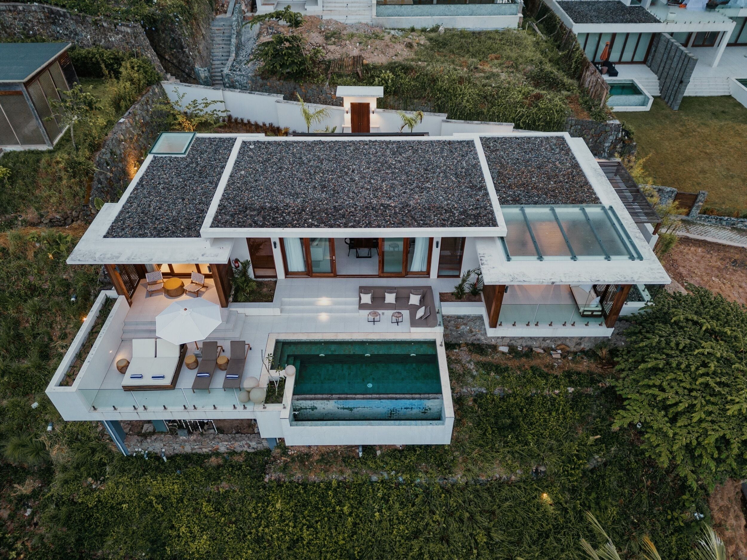 A modern house with a swimming pool, outdoor seating, and a stone facade.