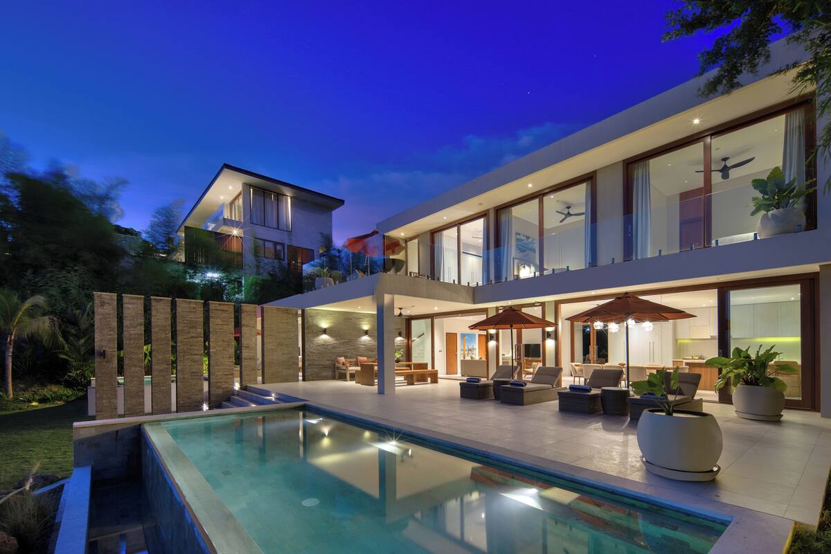 Una casa moderna con piscina, mobiliario de exterior y ventanas amplias.