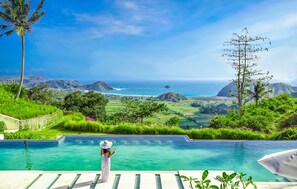 Une piscine avec vue sur l’océan et les collines.