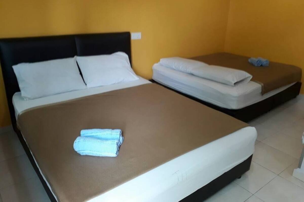 A room with two beds, one with a brown mattress and the other with a white mattress.
