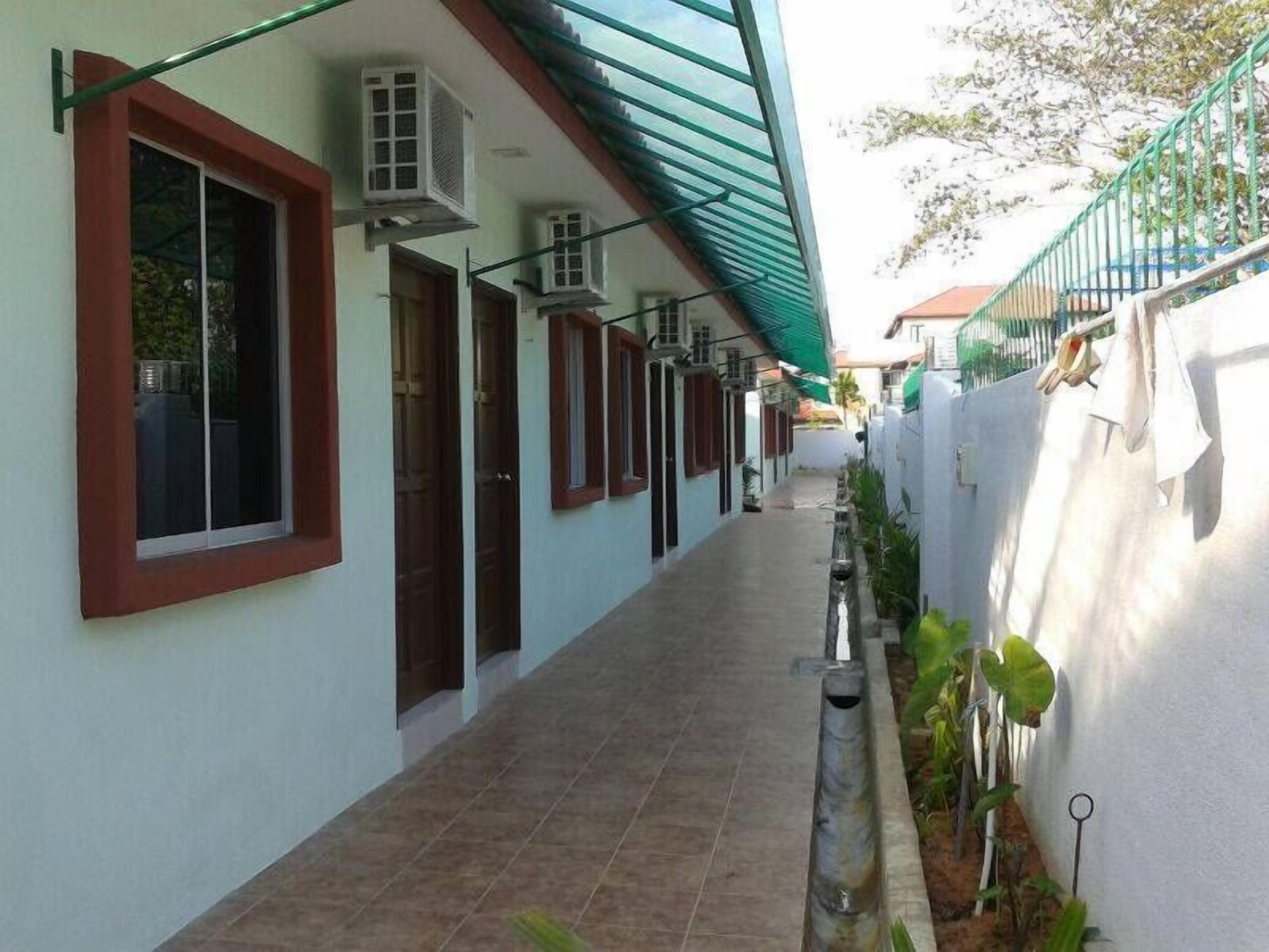 A corridor with a tiled floor, air conditioning units, and a green awning.