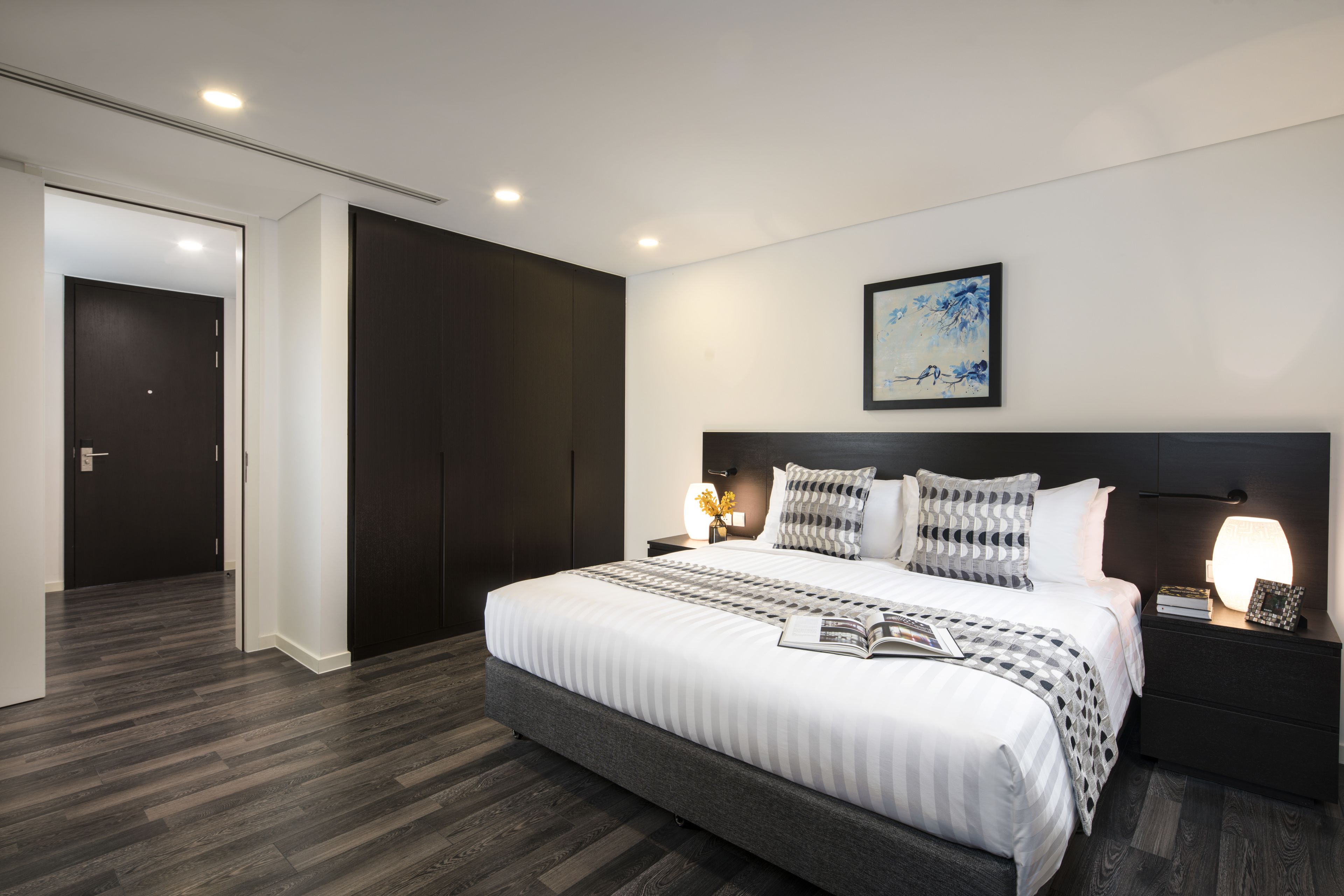 Ein modernes Schlafzimmer mit einem großen Bett, dunklem Holzboden und einem minimalistischen Design.