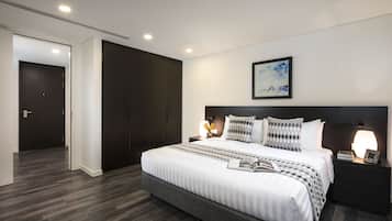Ein modernes Schlafzimmer mit einem großen Bett, dunklem Holzboden und einem minimalistischen Design.