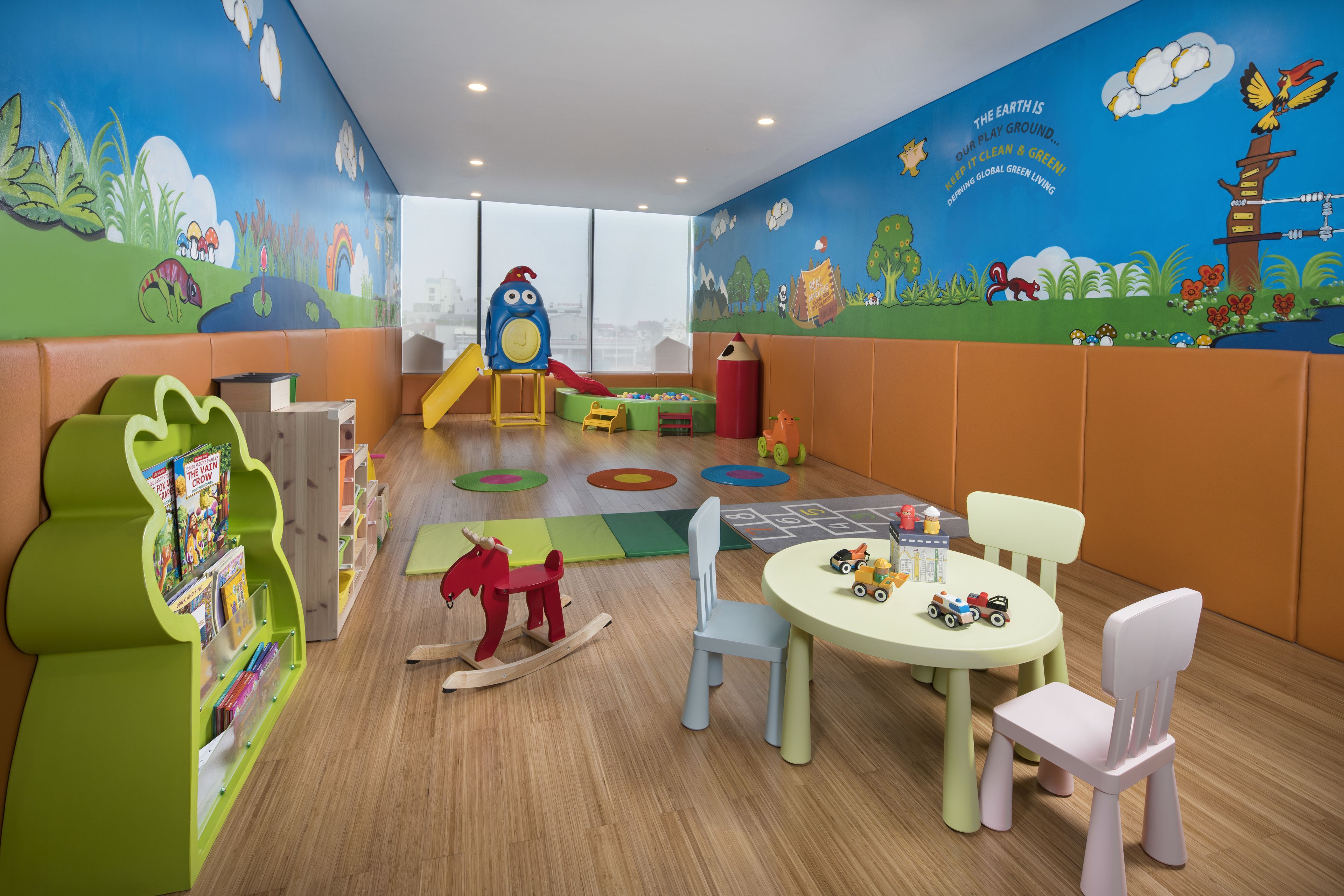 A children's playroom with a slide, play mats, and a table with toys.