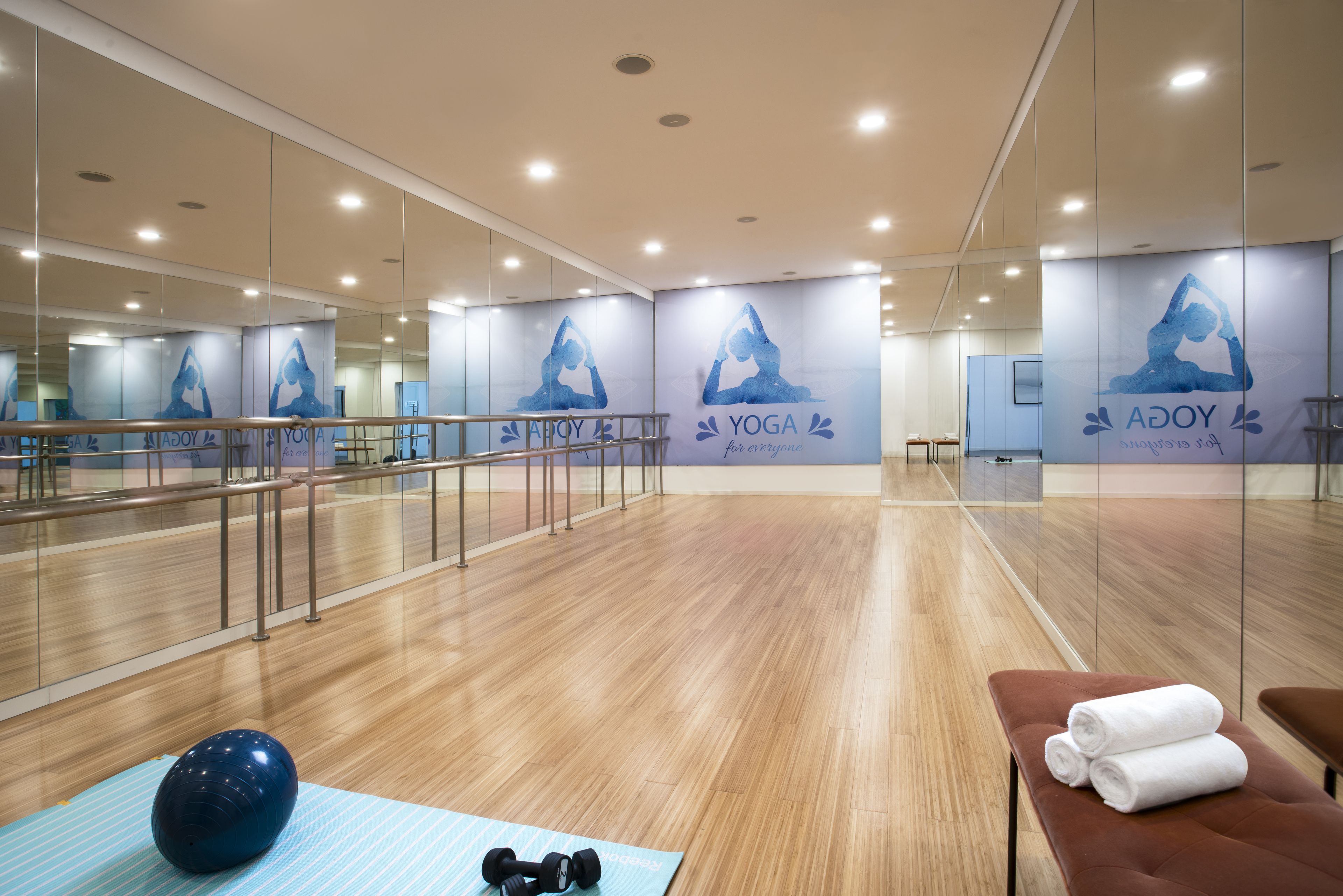 Un studio de yoga doté de murs et d’un plafond recouverts de miroirs, ainsi que de planchers en bois.
