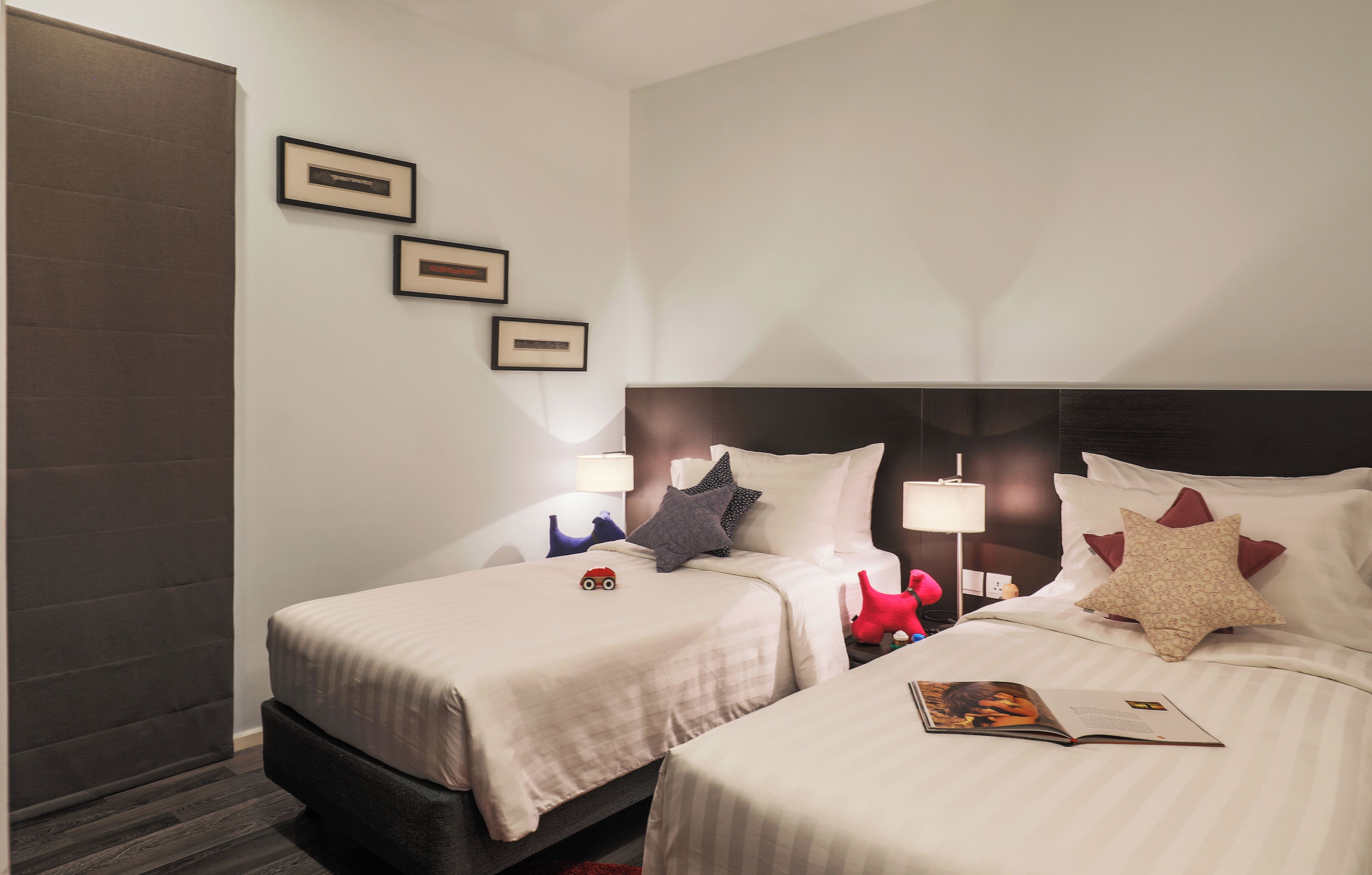 A hotel room with two beds, a large headboard, and framed pictures on the wall.