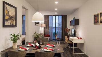 A modern hotel room with a dining area, a sofa, a TV, and a balcony with a view.