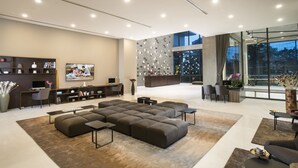 Un soggiorno moderno con un divano componibile, una televisione a schermo piatto, una scrivania e un'area reception con parete di vetro.