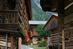 A traditional wooden building with a stone foundation, wooden balconies, and a mountain backdrop. - Albergo Diffuso Sauris di Sotto (Sauris)