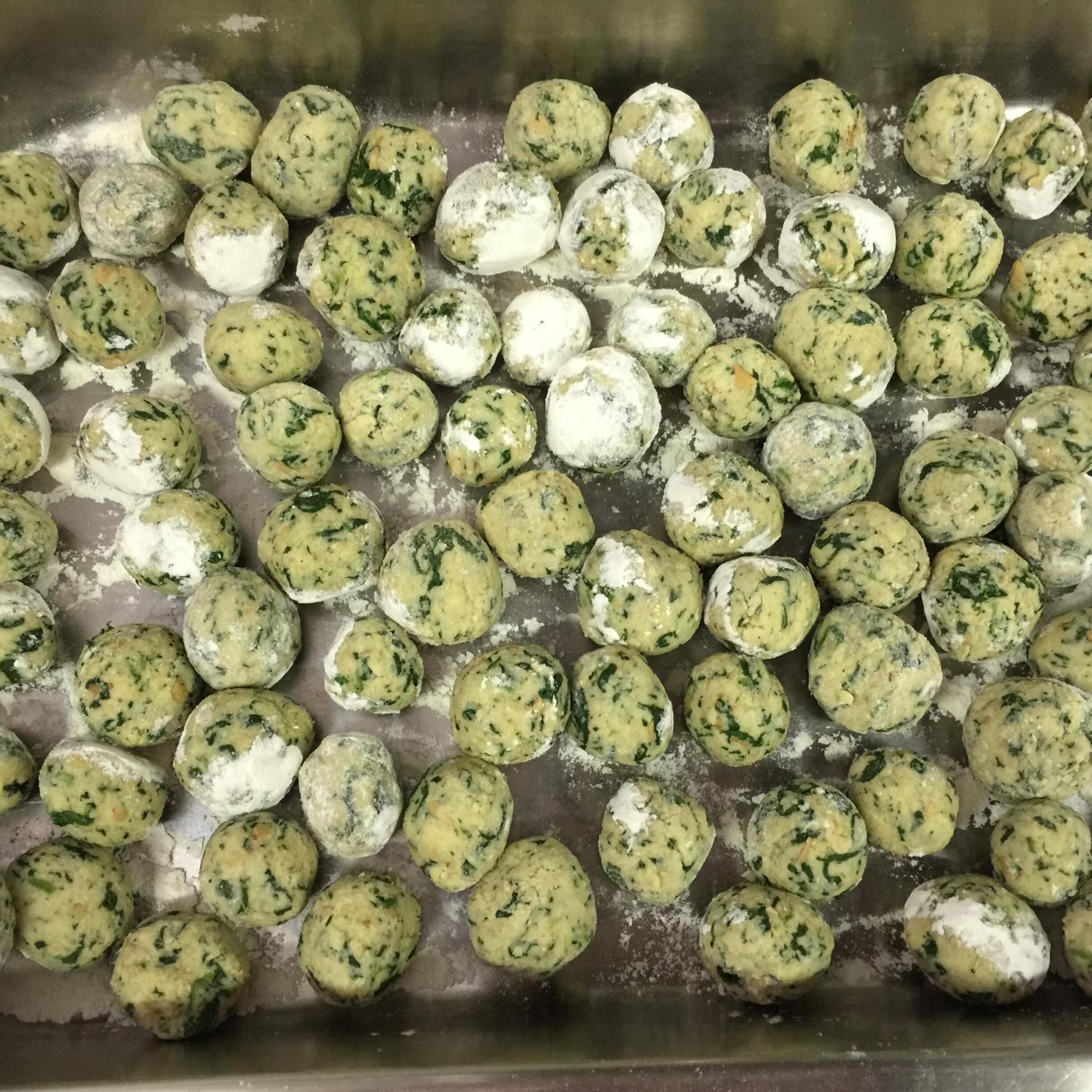 Une assiette contenant des aliments ronds, verts et blancs, peut-être une sorte de ravioli ou de pâtisserie, disposés les uns à côté des autres.