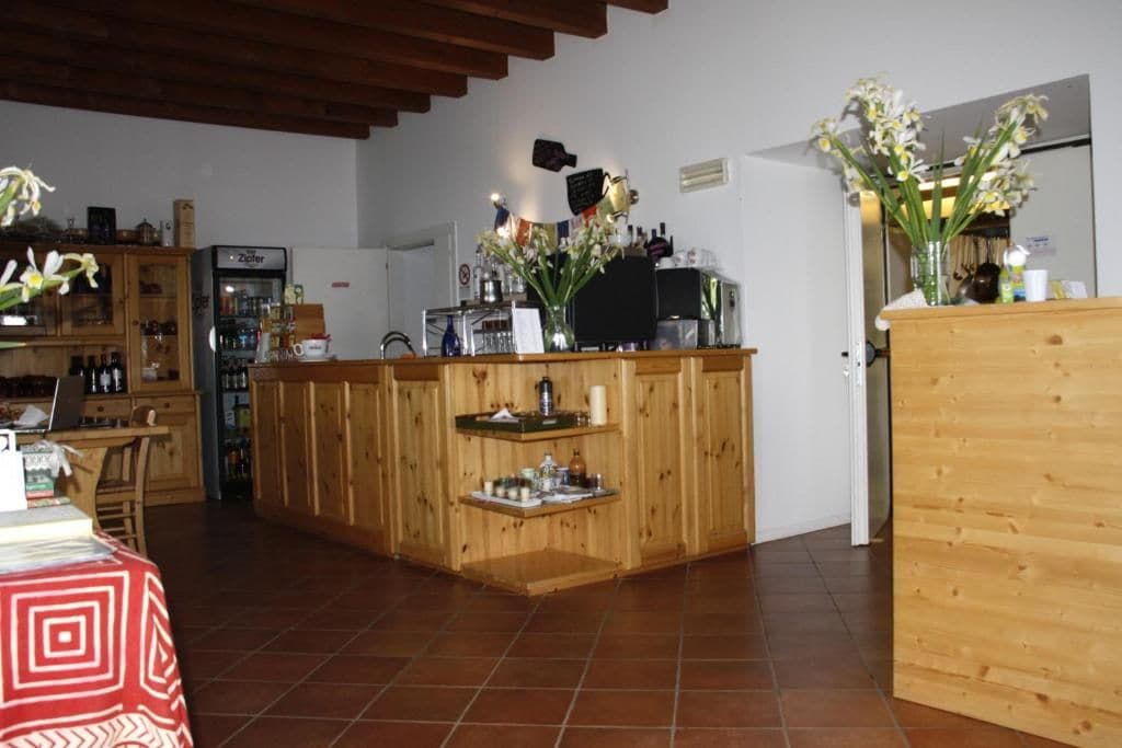 A kitchen with wooden cabinets, a refrigerator, a coffee machine, and a dining area with a table and chairs.