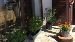 A patio with potted plants, a wooden table, and a door. - Malga Zanga (Arco)